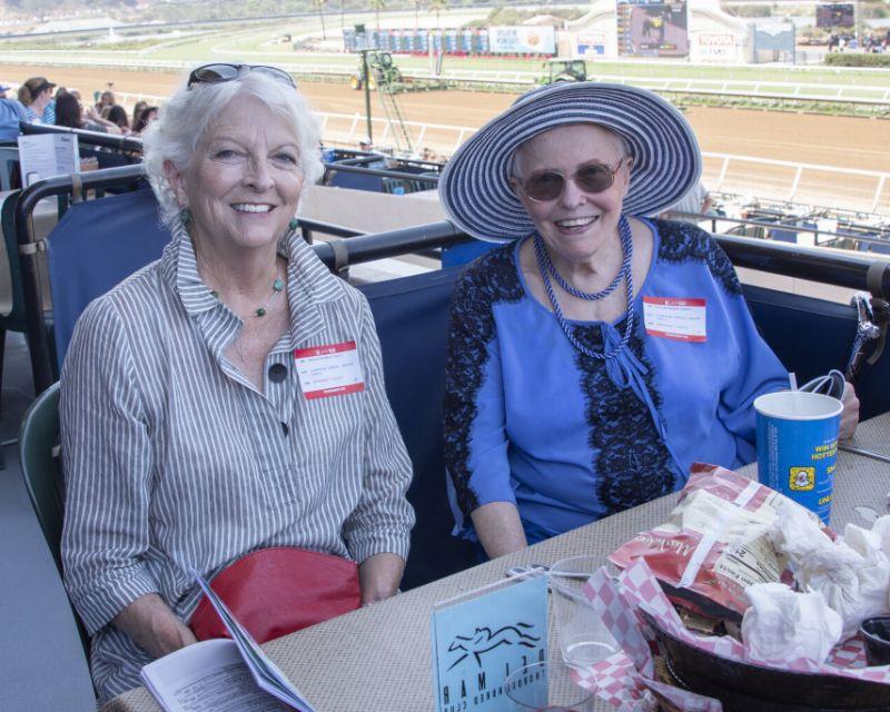 two guests at races and one with a blue hat