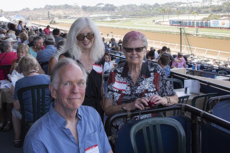 three guests at a table overlooking the track